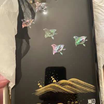 Sale Photo Thumbnail #141: Japanese black lacquer box lid featuring mother-of-pearl plover inlays and gold maki-e stylized waves, presented in its original packaging.
