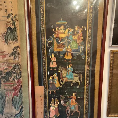 Sale Photo Thumbnail #145: Framed Indian miniature painting on black fabric, depicting a royal procession with elephants, horses, and camels, housed in a reddish-brown wooden frame with a brass hanger.