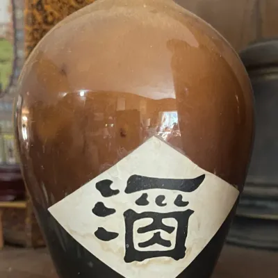 Sale Photo Thumbnail #176: Vintage Asian glazed ceramic sake bottle featuring a two-tone brown and black finish with handwritten calligraphic character label.