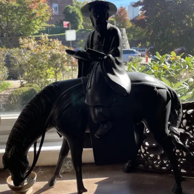 Sale Photo Thumbnail #32: Dark cast metal or bronze figurine depicting a scholar sitting atop a horse drinking from a small bowl.