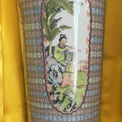 Sale Photo Thumbnail #177: Vintage Chinese porcelain meiping vase featuring detailed geometric patterns, a gilded rim, and a painted medallion scene of a figure playing a flute, resting on a carved wooden base.