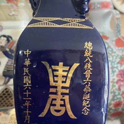 Sale Photo Thumbnail #171: Cobalt blue ceramic vase featuring gilt Chinese calligraphy and handles, created as a commemorative piece.