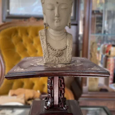 Sale Photo Thumbnail #8: Asian-style carved stone Guanyin bust sculpture presented on a dark wood pedestal stand with mother-of-pearl inlay.