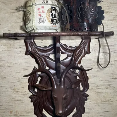 Sale Photo Thumbnail #53: Hand-carved Black Forest style wooden wall bracket featuring a deer head motif, holding a mini Gekkeikan sake barrel and a small decorative lantern.