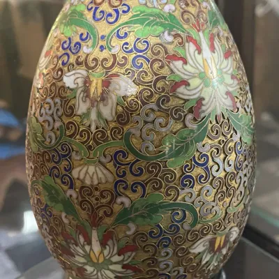 Sale Photo Thumbnail #182: Vintage brass cloisonné decorative egg featuring intricate floral motifs and filigree wirework, displayed on a wooden stand.