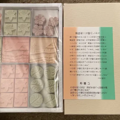 Sale Photo Thumbnail #82: Boxed set of traditional Japanese higashi sugar candies featuring molded floral, leaf, and architectural designs, presented with original packaging and inserts.