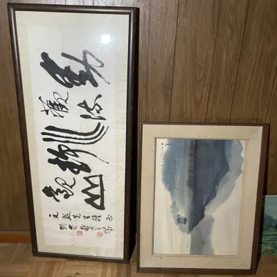 Sale Photo Thumbnail #56: Pair of framed Asian artworks, including a vertical calligraphy piece with red seal stamps and a muted landscape painting of mountains and water.
