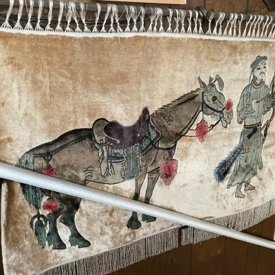 Sale Photo Thumbnail #70: Vintage Asian velvet wall hanging tapestry featuring a horse and rider motif, trimmed with fringe and mounted on a curtain rod.