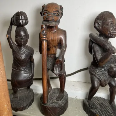Sale Photo Thumbnail #136: Trio of hand-carved dark wood African-style tribal figurines depicting figures in traditional activities, standing on integrated bases.