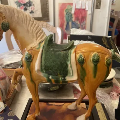 Sale Photo Thumbnail #140: Tang dynasty-style ceramic horse statue with glazed amber and green accents, mounted on a dark wooden base.