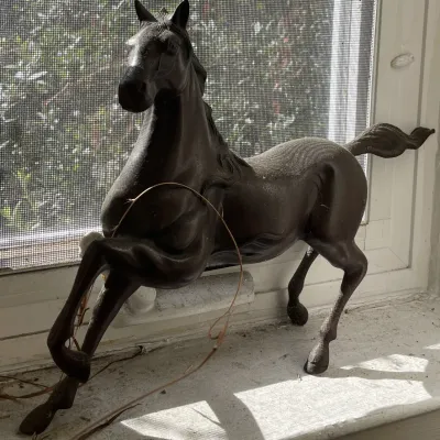 Sale Photo Thumbnail #29: Cast metal rearing horse figurine with a dark bronze patina, displayed on a windowsill.