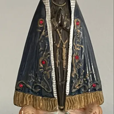 Sale Photo Thumbnail #103: Polychrome statue of Our Lady of Aparecida featuring a dark navy blue embroidered mantle with red rhinestone accents, a ornate golden crown, and cherubs at the base.