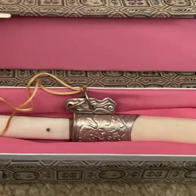 Sale Photo Thumbnail #90: Vintage Asian decorative short sword featuring a carved bone-style handle and sheath with ornate metal fittings, complete with a red tassel and silk-lined brocade presentation box.