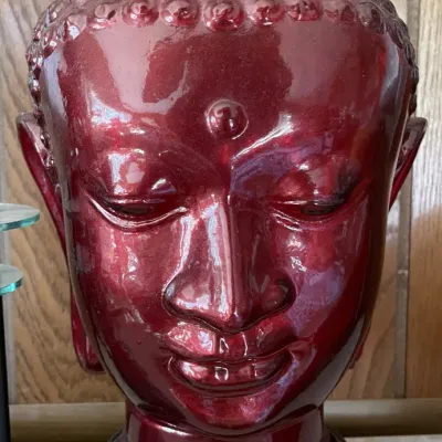 Sale Photo Thumbnail #14: Red glazed ceramic Buddha head sculpture mounted on a dark wooden base.