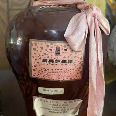 Sale Photo Thumbnail #180: Vintage Pagoda Brand Shao Hsing rice wine in a brown glazed ceramic vessel, decorated with a pink ribbon.