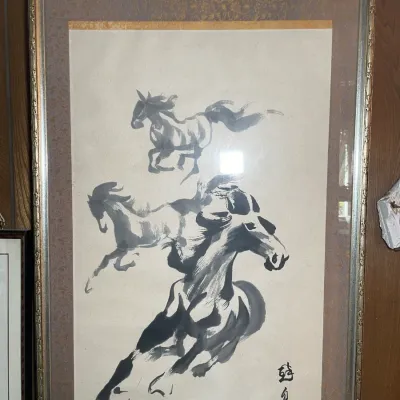 Sale Photo Thumbnail #72: Framed Asian sumi-e ink wash painting depicting galloping horses, featuring artist calligraphy and a red seal stamp, presented under glass in a metallic silver-tone frame.