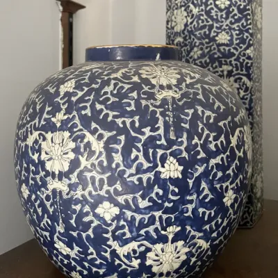 Sale Photo Thumbnail #110: Pair of blue and white ceramic vessels featuring intricate floral and vine scrollwork, including a bulbous jar and a tall hexagonal vase with gold trim.