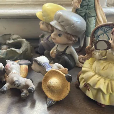 Sale Photo Thumbnail #169: Collection of vintage porcelain and ceramic figurines, including children in hats and donkeys with pack saddles.