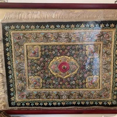 Sale Photo Thumbnail #155: Framed vintage Asian embroidered textile artwork featuring intricate zardozi metallic thread, beads, and cabochons surrounded by a fringed border in a dark reddish-brown wood frame.