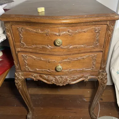 Sale Photo Thumbnail #63: French Provincial style two-drawer wooden nightstand featuring ornate carved detailing, brass knobs, and cabriole legs.