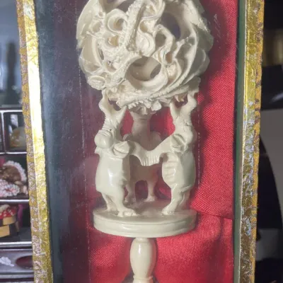 Sale Photo Thumbnail #190: Intricately carved Chinese puzzle ball on an ornate pedestal stand, housed in a glass and red silk display box.