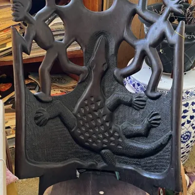 Sale Photo Thumbnail #31: Hand-carved African tribal chair featuring intricate motifs of figures and a central crocodile design in dark wood.