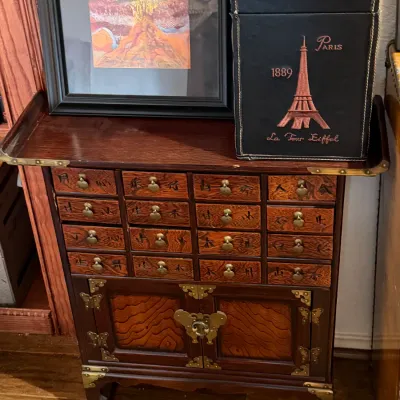 Sale Photo Thumbnail #122: Asian-style wooden apothecary chest featuring multiple drawers with metal hardware and character details.