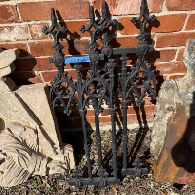 Sale Photo Thumbnail #403: Two Gothic revival style black cast iron fence toppers with finials, resting against a brick wall