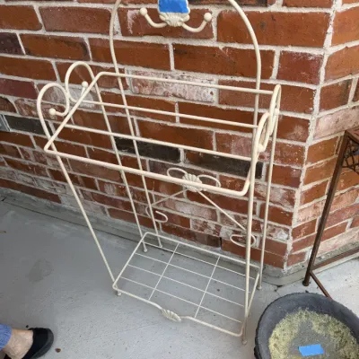 Sale Photo Thumbnail #392: Off-white wrought iron freestanding towel rack or baker's rack featuring decorative scrollwork and a bottom wire shelf.