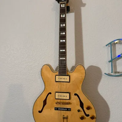 Sale Photo Thumbnail #100: Epiphone Casino archtop electric guitar in natural blonde finish, featuring P-90 pickups, gold hardware, split parallelogram inlays, and a wall mount.