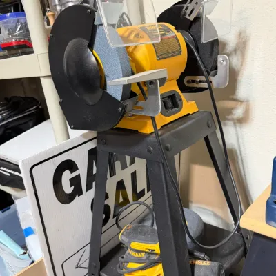 Sale Photo Thumbnail #304: DeWalt bench grinder mounted on a black metal tool stand, featuring eye shields and dual grinding wheels, paired with a DeWalt orbital sander stored on the lower shelf.