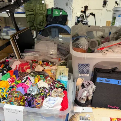 Sale Photo Thumbnail #364: Collection of crafting supplies including a plastic tub filled with rolled fabric scraps, a clear tote with ribbons, and a DasKid zippered case containing gel pens.