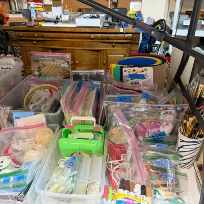 Sale Photo Thumbnail #360: Assortment of crafting supplies, including paintbrushes, hot glue sticks, yarn, markers, and foam sheets stored in plastic bins.