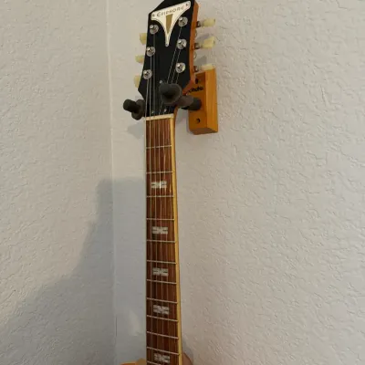 Sale Photo Thumbnail #98: Epiphone hollow-body electric guitar with split-block fretboard inlays, displayed on a wooden wall-mount hanger. (Pic 2)