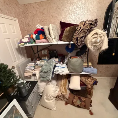 Sale Photo Thumbnail #277: Collection of household linens, decorative throw pillows, folded blankets, and bed pillows displayed on plastic folding tables.