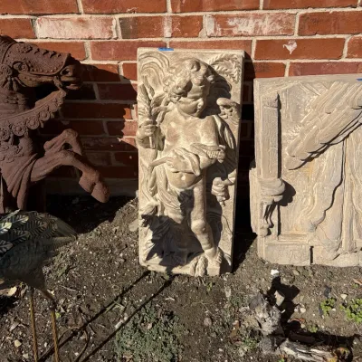 Sale Photo Thumbnail #398: Cast stone cherub wall relief panel leaning against a brick wall.