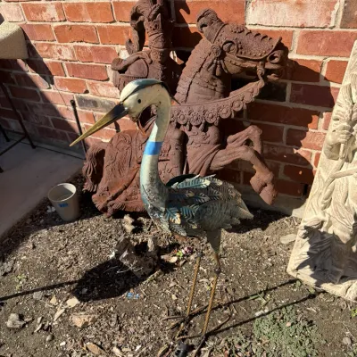Sale Photo Thumbnail #397: Painted metal heron garden statue standing in front of a knight on horseback sculpture.