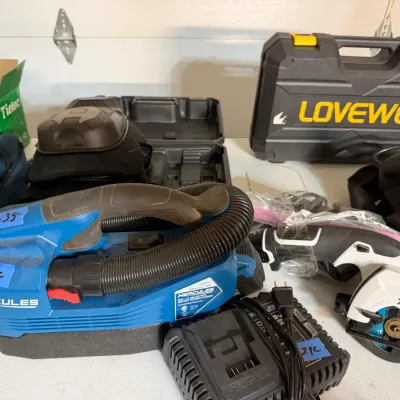 Sale Photo Thumbnail #348: Collection of power tools and equipment, including a blue Hercules 20V cordless wet/dry vacuum with charger, a Makita cordless compact circular saw, knee pads, and hard molded carrying cases.