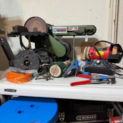 Sale Photo Thumbnail #300: Central Machinery belt and disc sander arranged on a workbench alongside a red mini bench grinder and assorted hand tools.
