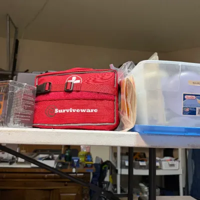 Sale Photo Thumbnail #361: Collection of emergency prep and home items including a red Survive ware first aid kit, and a Sterlite plastic tote filled with light bulbs.