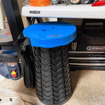 Sale Photo Thumbnail #301: Portable collapsible stool in black and blue plastic with attached carrying strap.