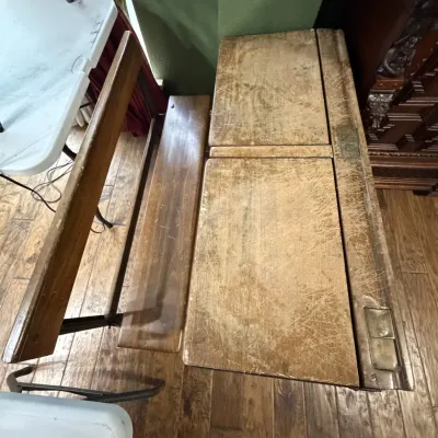 Sale Photo Thumbnail #8: Vintage double wooden school desk with attached bench seating, featuring a heavily distressed surface with heavy scratches and wear consistent with age and use.