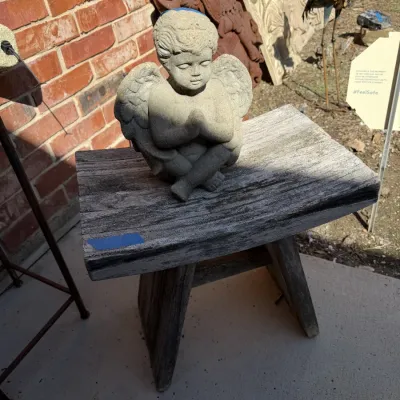 Sale Photo Thumbnail #394: Concrete praying cherub garden statue sitting on a weathered rustic wooden bench.