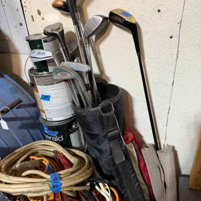 Sale Photo Thumbnail #338: Collection of vintage golf clubs in a bag alongside extension cords and jumper cables.