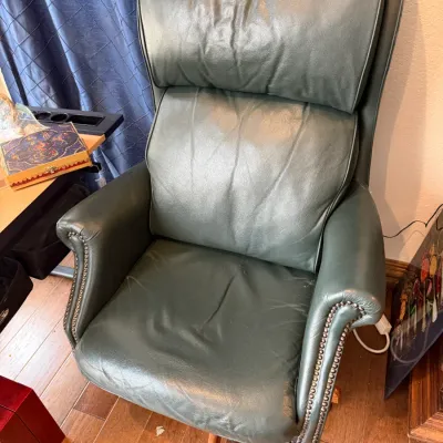 Sale Photo Thumbnail #137: Dark green leather high-back office chair featuring nailhead trim detailing and a swivel-wheeled base.