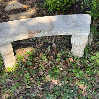 Sale Photo Thumbnail #285: Curved concrete garden bench with molded scrollwork details, showing outdoor weathering and patina.