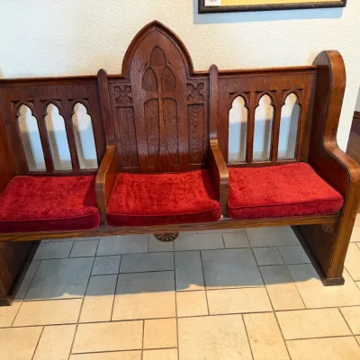 Sale Photo Thumbnail #26: Antique Gothic Revival carved oak church pew bench, featuring three compartments with red velvet seat cushions and detailed arch tracery.