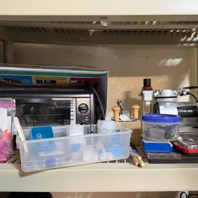 Sale Photo Thumbnail #310: Collection of crafting and hobby supplies, including a Sculpey clay oven, a Timbertech airbrush compressor, clay tools, and various storage containers on a plastic shelf.