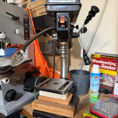 Sale Photo Thumbnail #322: Central Machinery 5-speed bench drill press with attached flexible work light, shown alongside workshop tools and accessories.