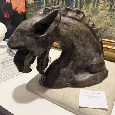 Sale Photo Thumbnail #199: Cast bronze bust sculpture of a Notre-Dame-style gargoyle, mounted on a square stone display base.